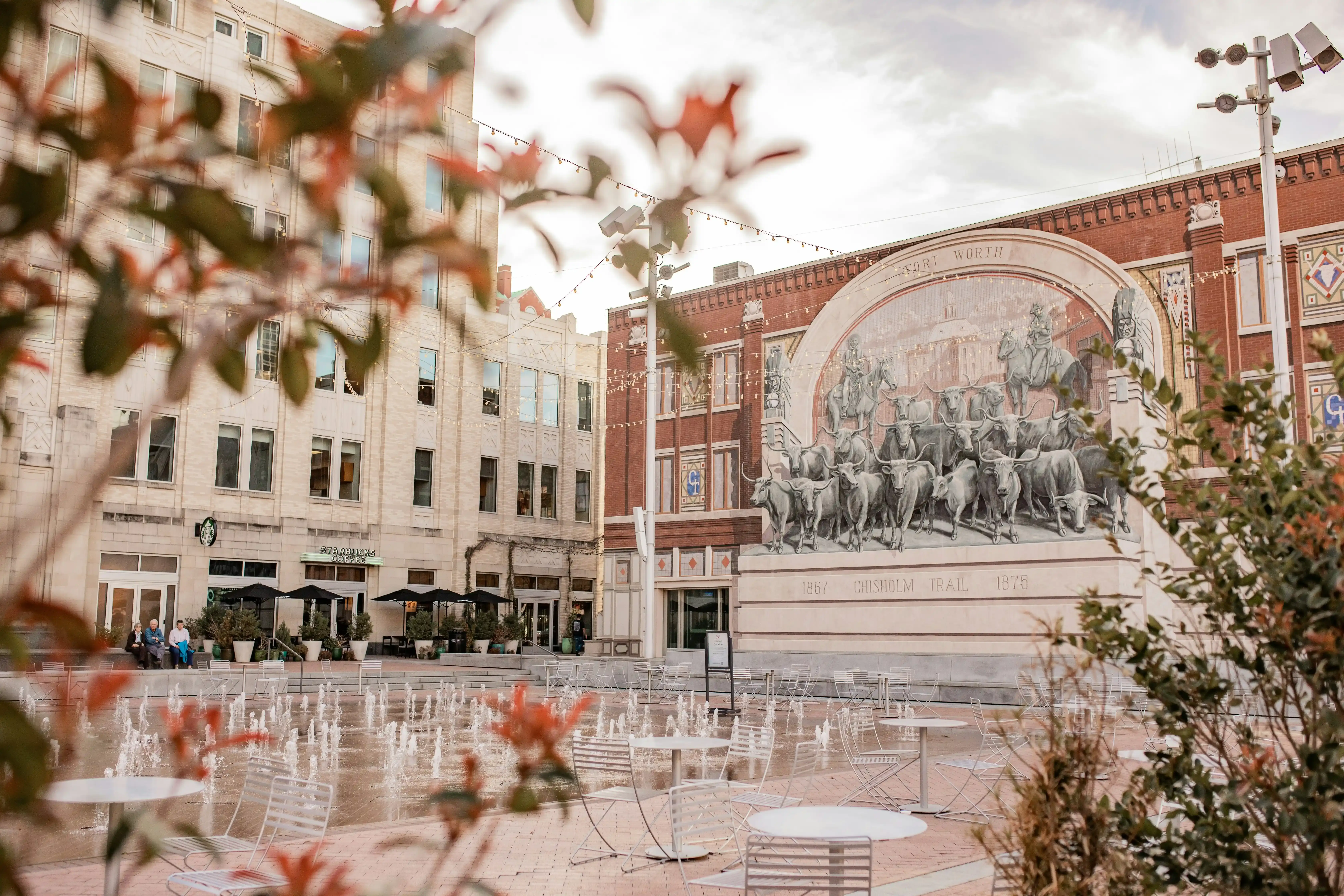 Ground view of a plaza with a mural in the background in Fort Worth
