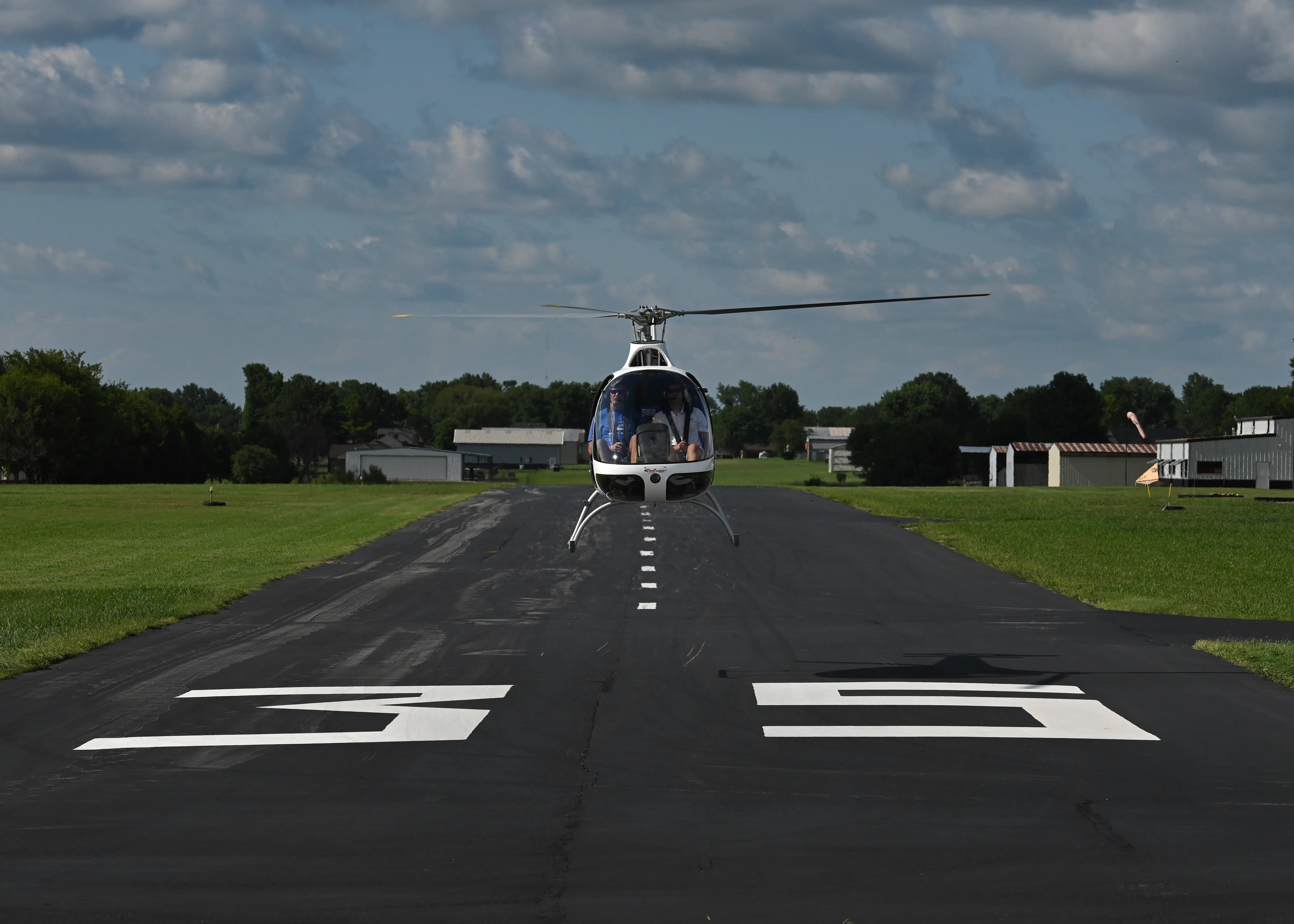 Front view of helicopter taking off over runway